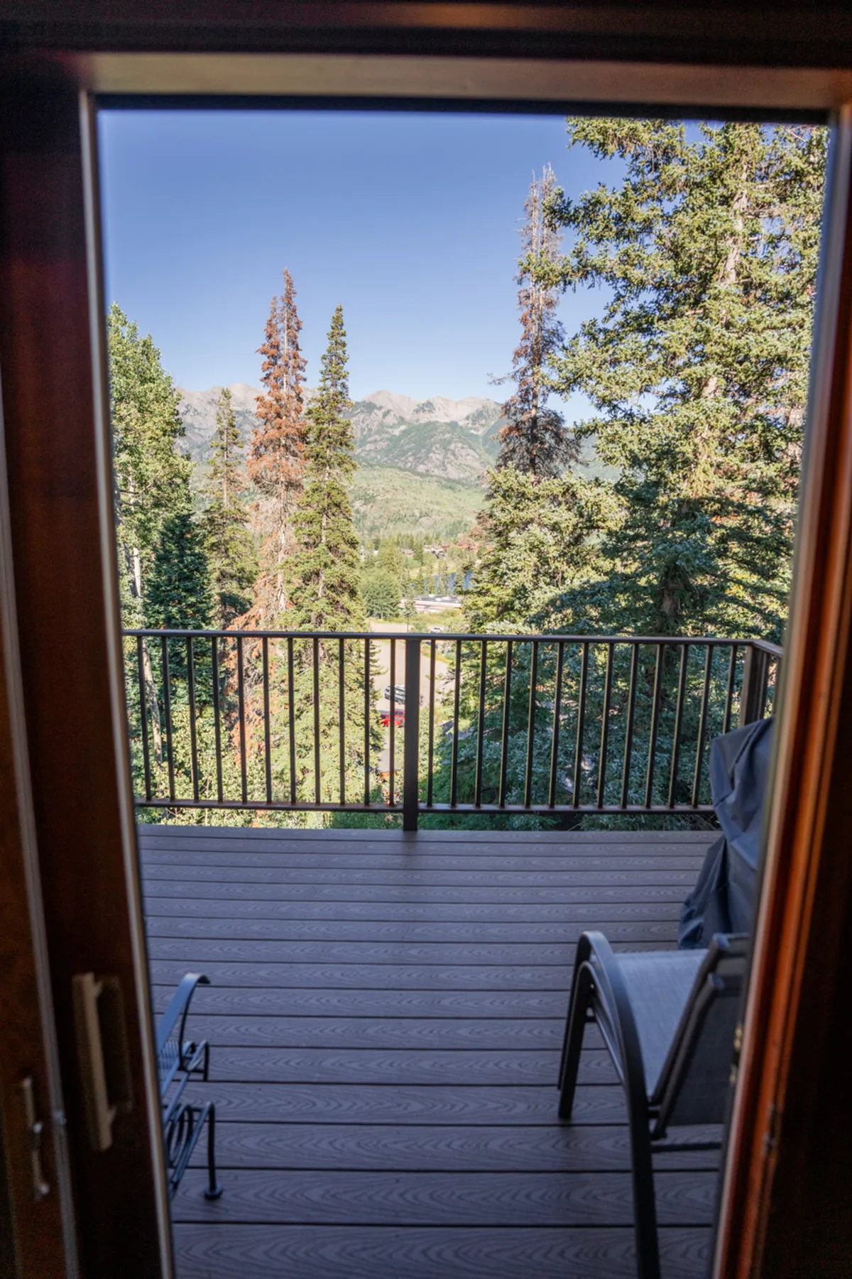 This exterior image showcases a deck area surrounded by tall trees, with unobstructed views of majestic mountains in the distance. The serene setting emphasizes tranquility and connection with nature, making it an ideal place to relax or enjoy the outdoors. The space is inviting for both quiet moments and small celebrations.
